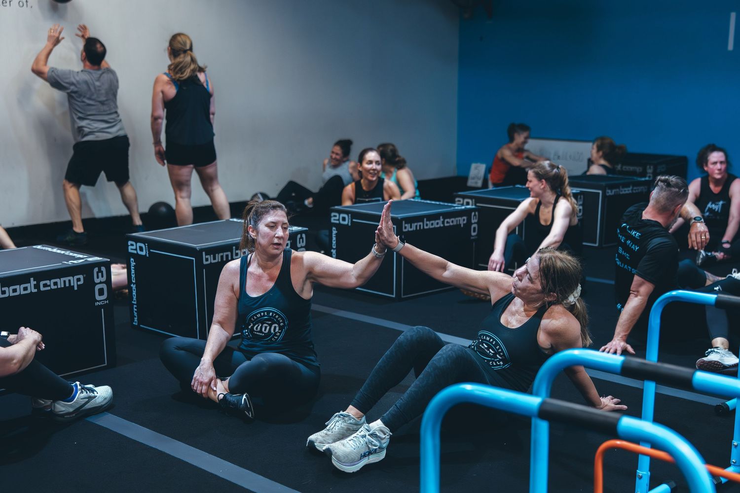 Group fitness participants using rowing machines during an intense workout class.
