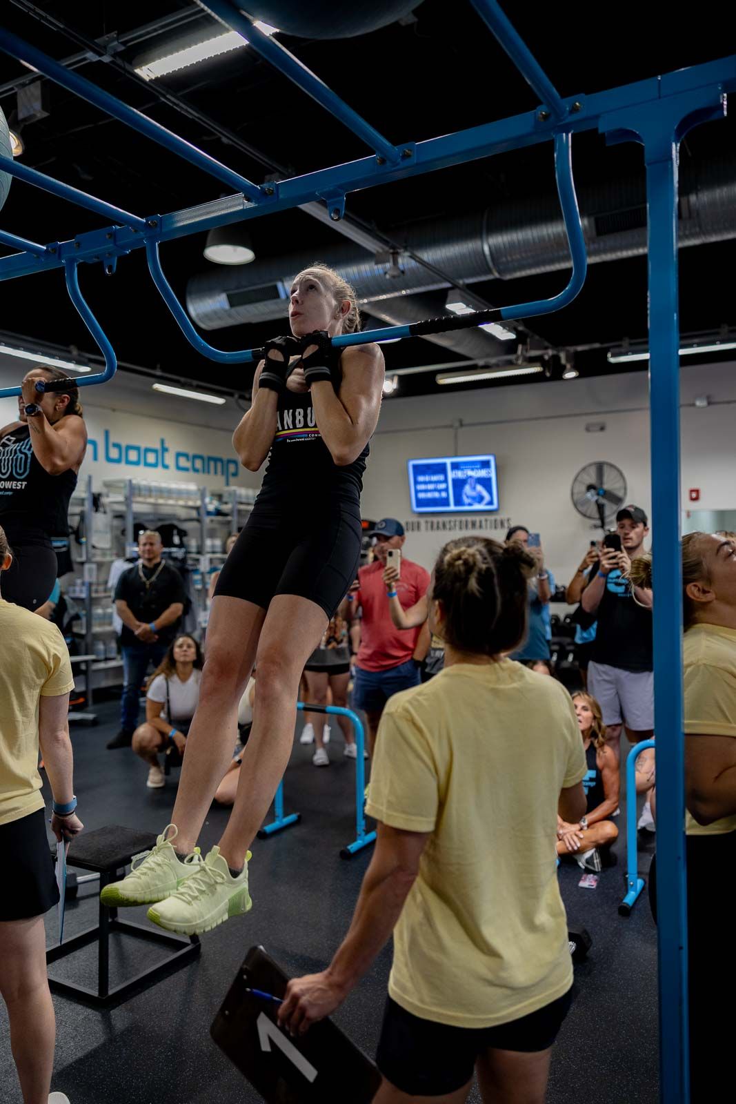 Athletes perform pull-ups during an intense workout session at a modern fitness facility.