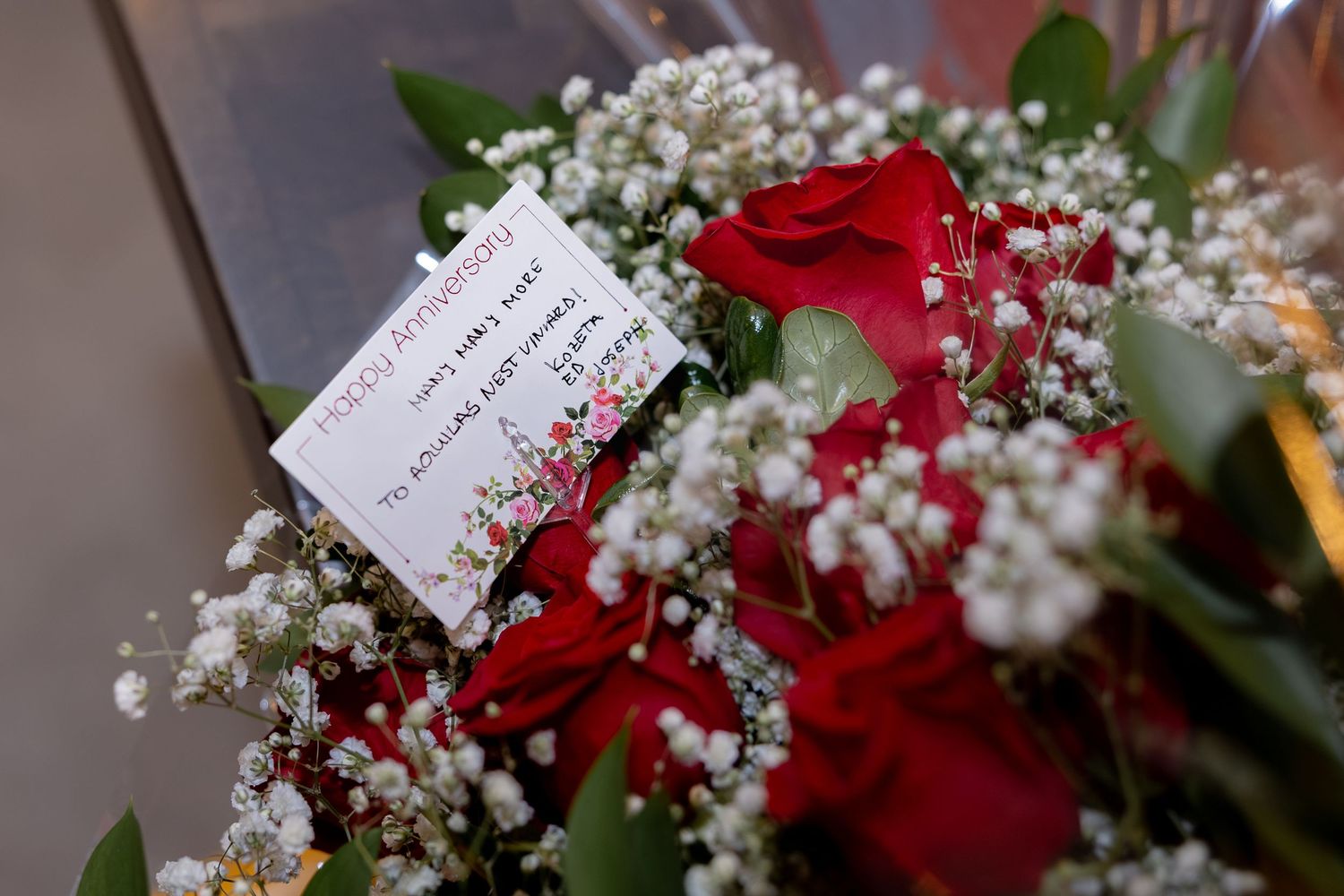 A bouquet of red roses accented with delicate white baby's breath flowers and green foliage.