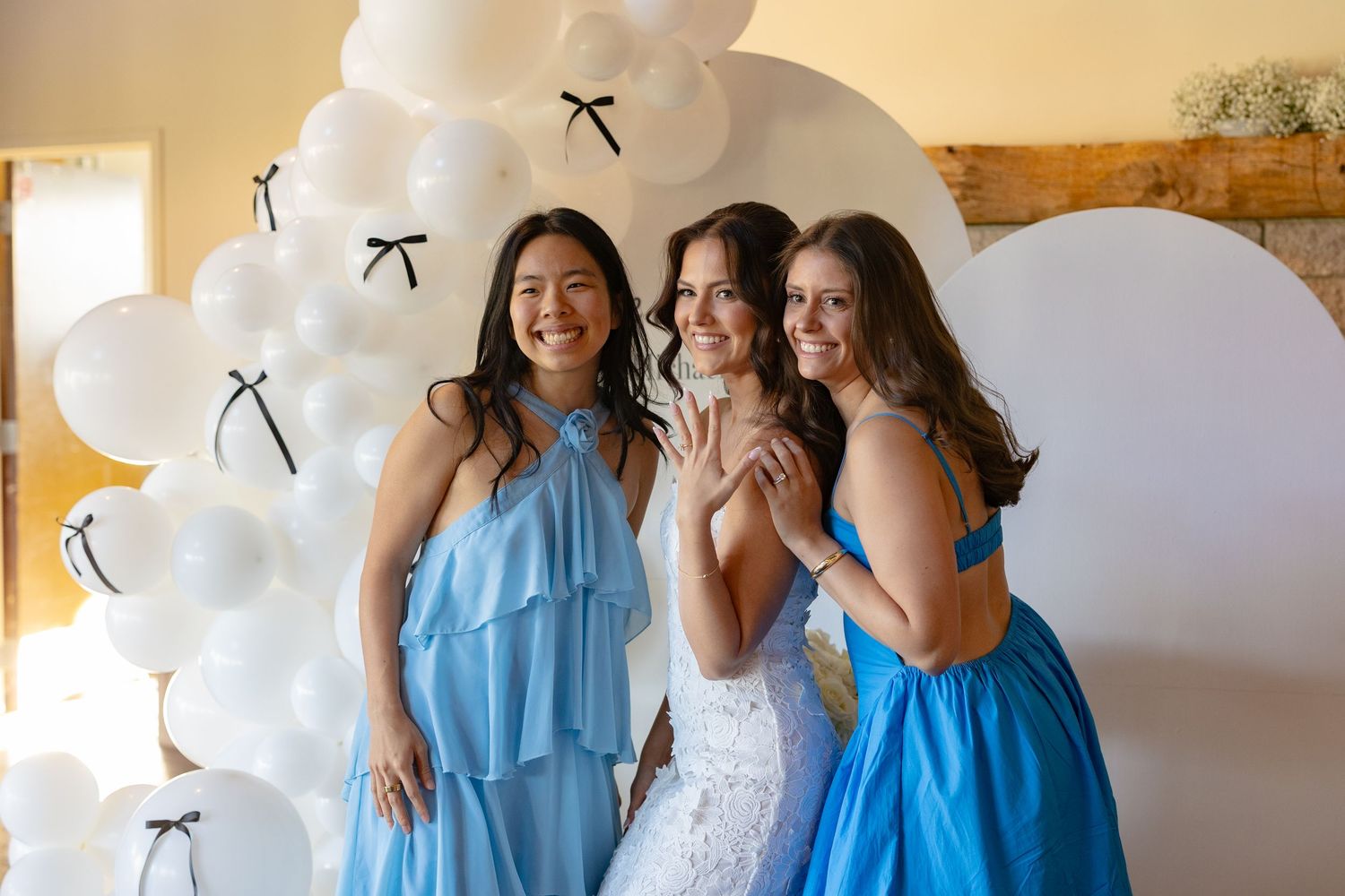 Wedding celebration with blue-dressed attendants and white balloons in a bright indoor venue.