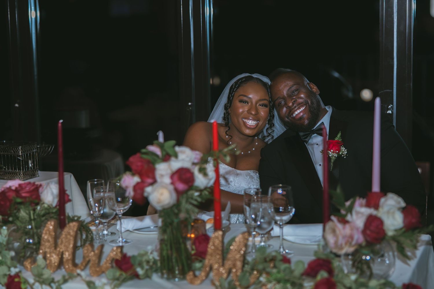 Bride and groom smiling at the camera at their dinner reception