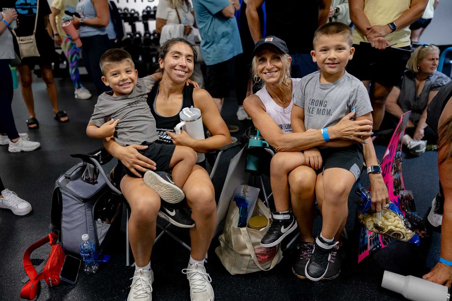 Group resting together on gym floor after workout session with backpacks and water bottles nearby.