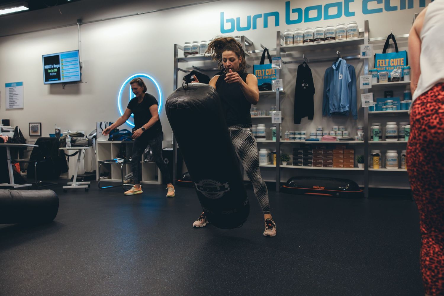 Fitness enthusiasts working out at Burn Boot Camp facility with branded wall signage.