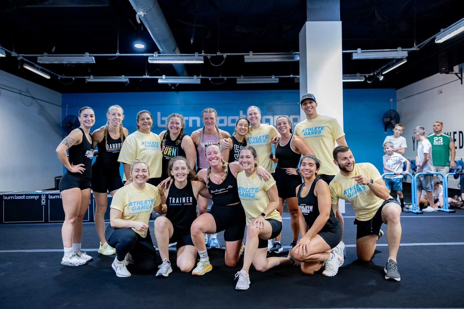 Large group of fitness enthusiasts pose together after a workout class in a modern gym space.