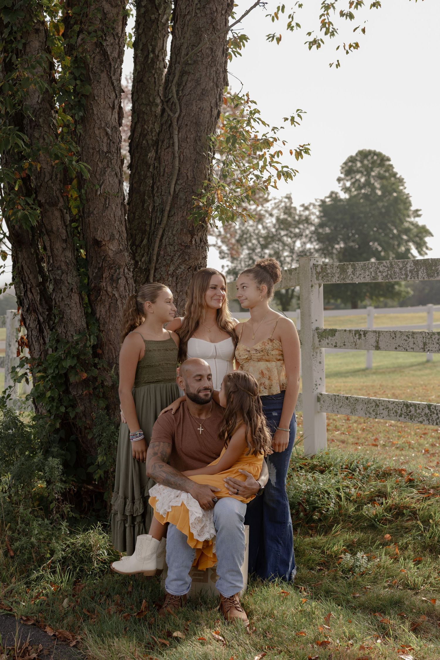 Family enjoying a casual outdoor photoshoot together in a park during autumn with fallen leaves around them.