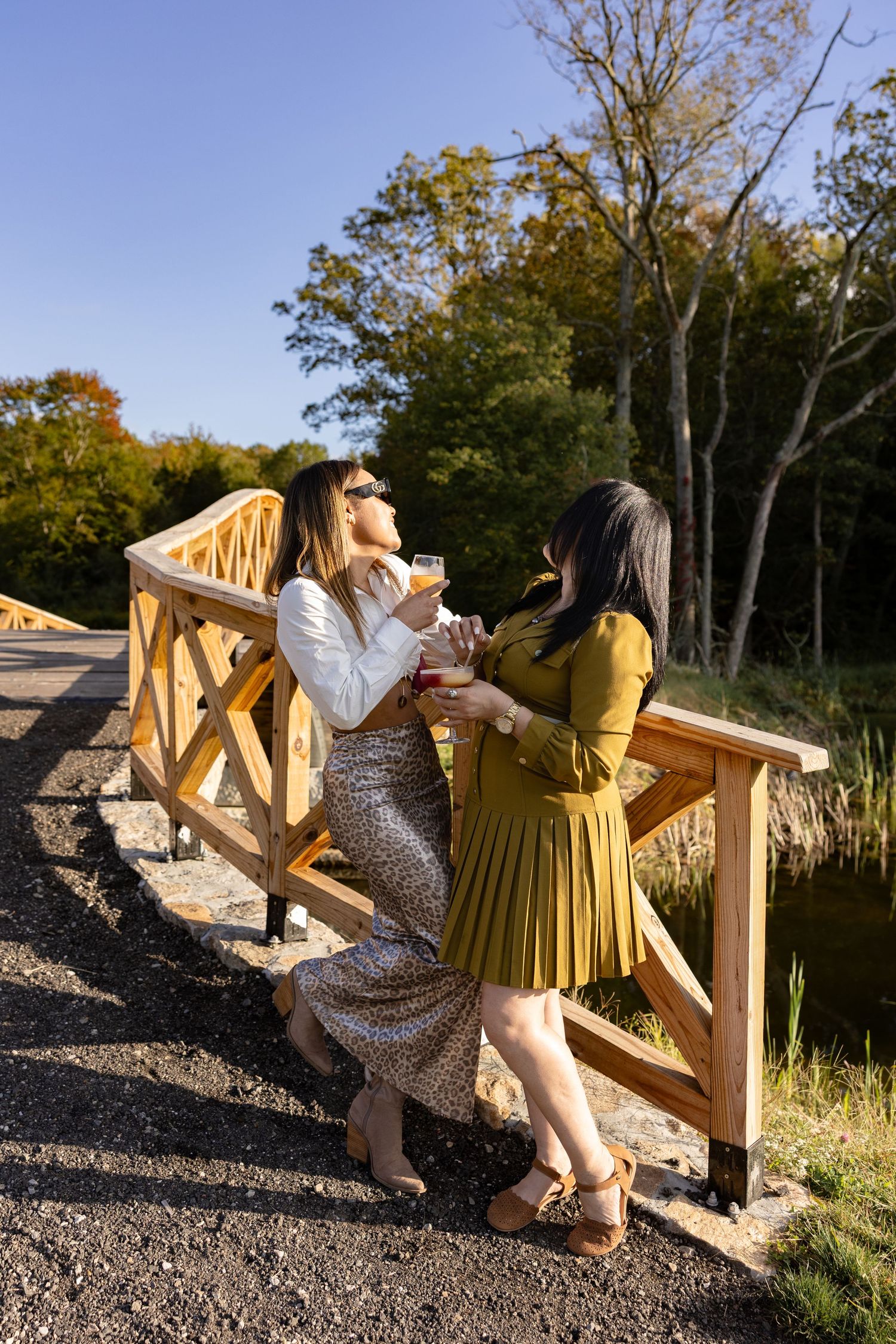 Two people in contrasting outfits sitting on wooden railings outdoors during autumn.