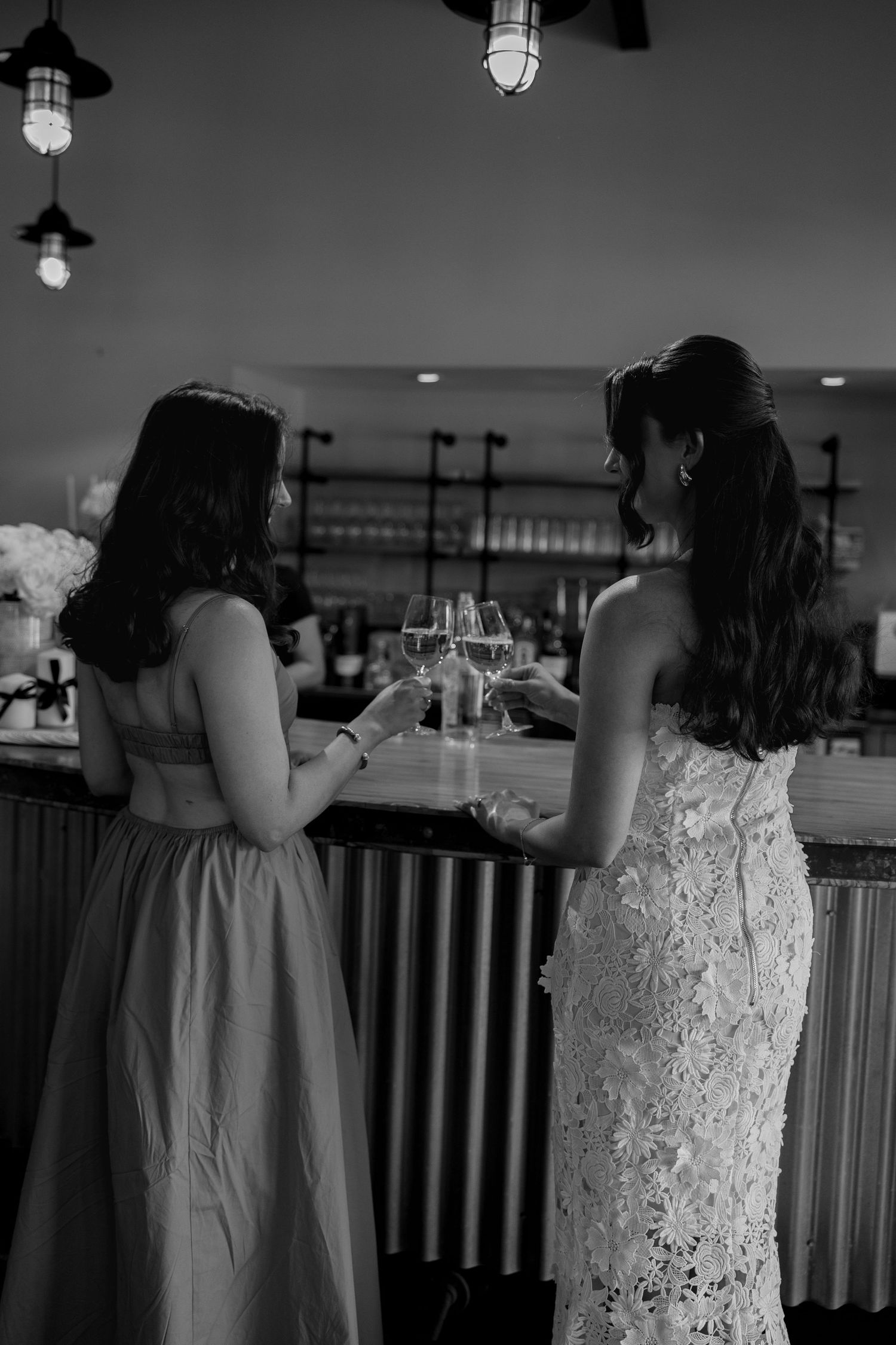 Black and white photos show guests mingling at an indoor reception venue with hanging lights.