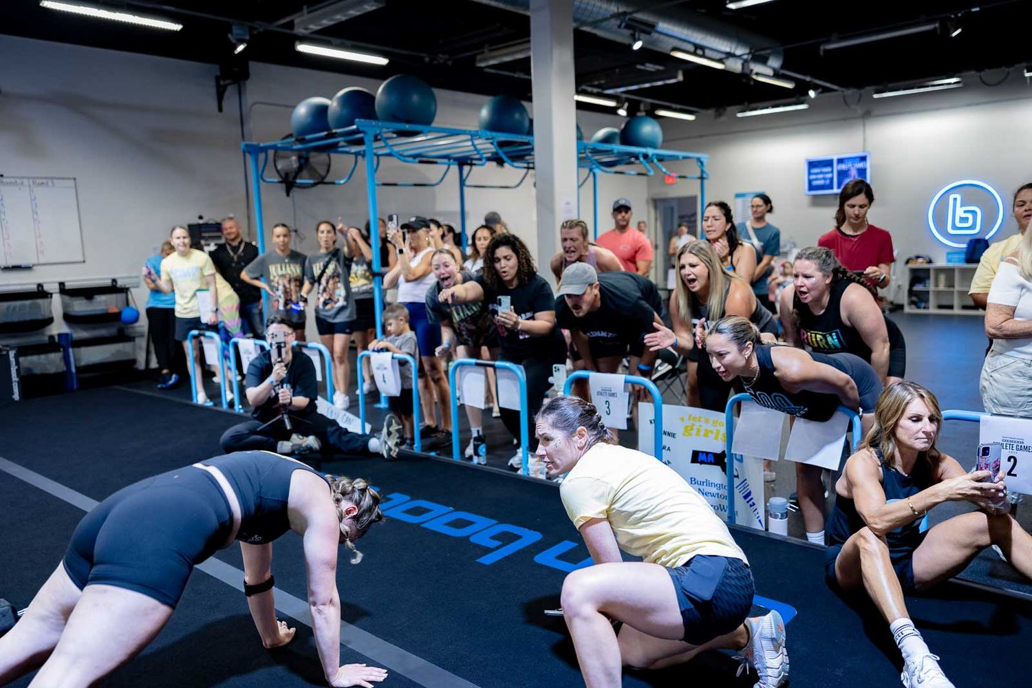 Fitness enthusiasts resting and recovering between workout sets in a modern gym facility.