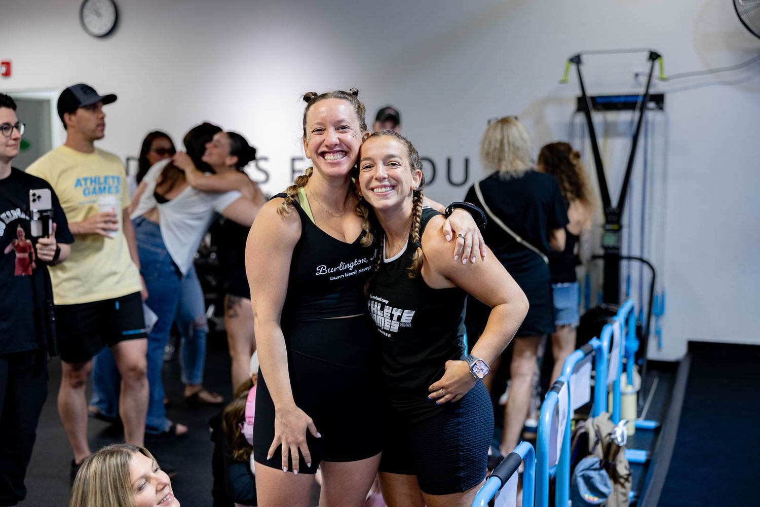 Two people sharing a joyful moment at a fitness studio with exercise equipment in the background.