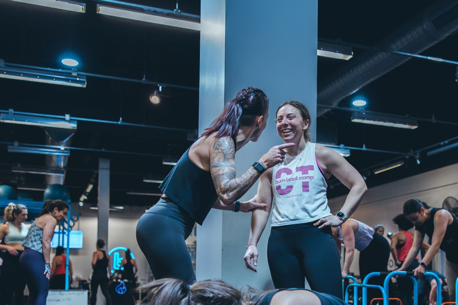 Excited participants celebrating during group workout session at indoor fitness facility.
