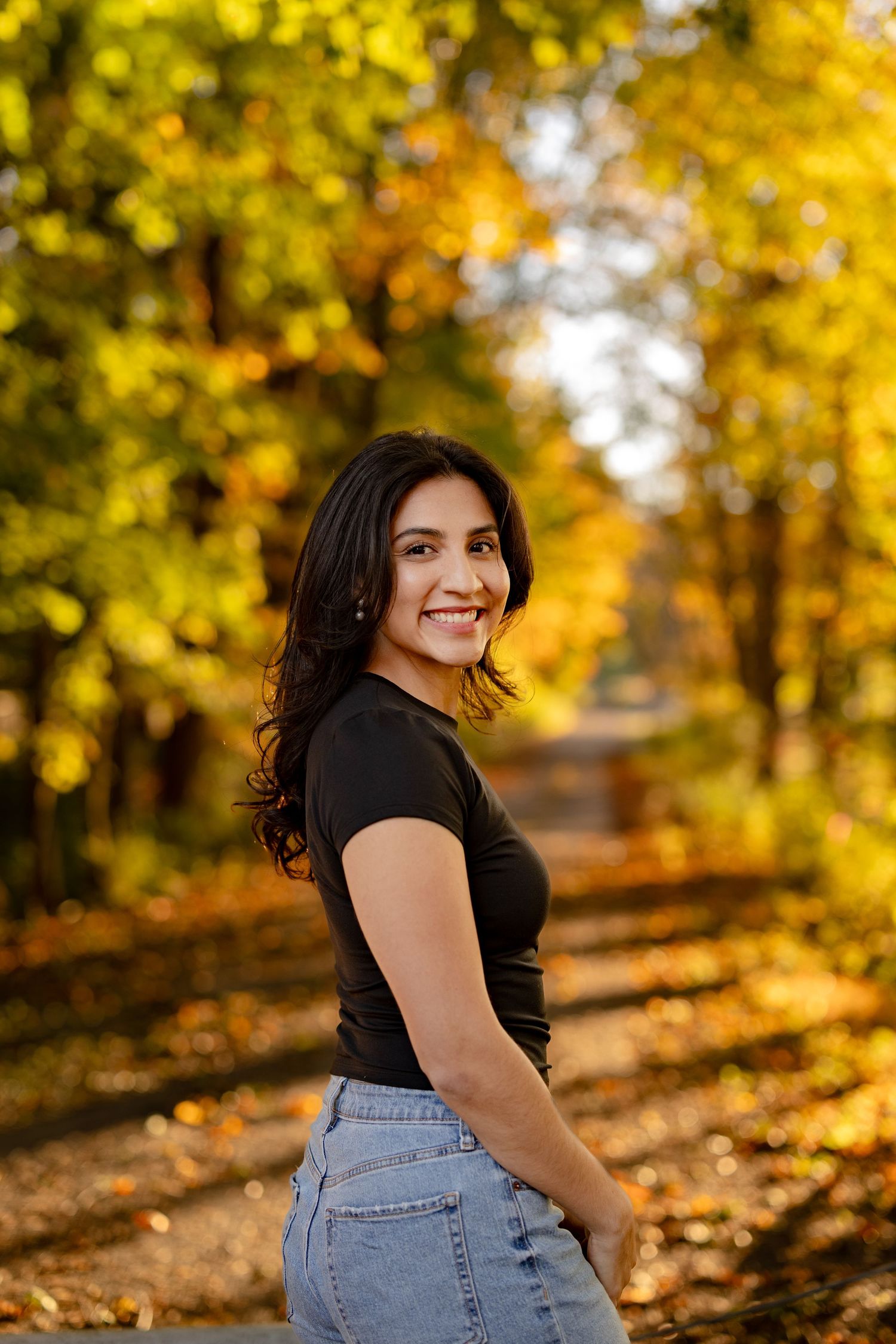 Autumn outdoor portrait session in a park with golden foliage and warm sunlight creating a dreamy atmosphere.