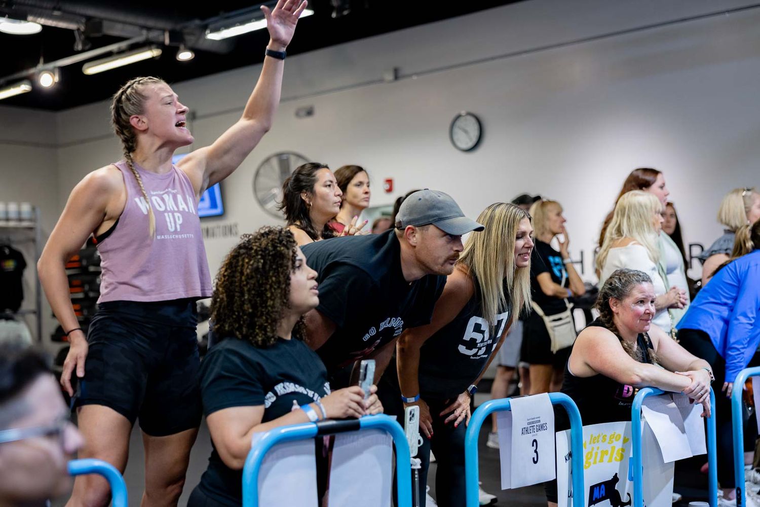 Enthusiastic crowd cheering and watching an indoor sporting competition at a gym facility.
