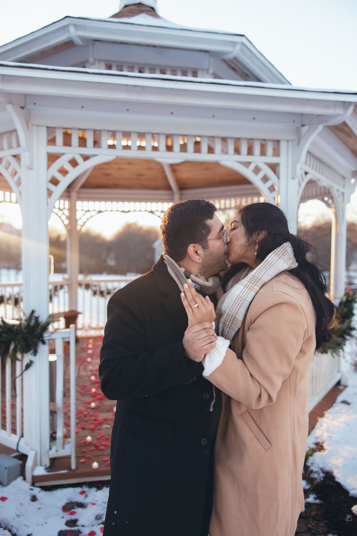 Romantic winter engagement photo in decorated white gazebo.