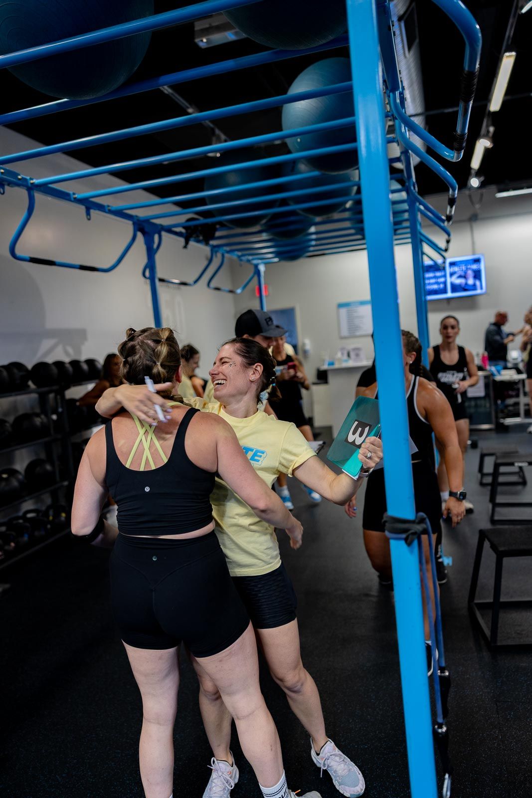 Athletes training in a gym with bright blue equipment while working on their mobility and form together.
