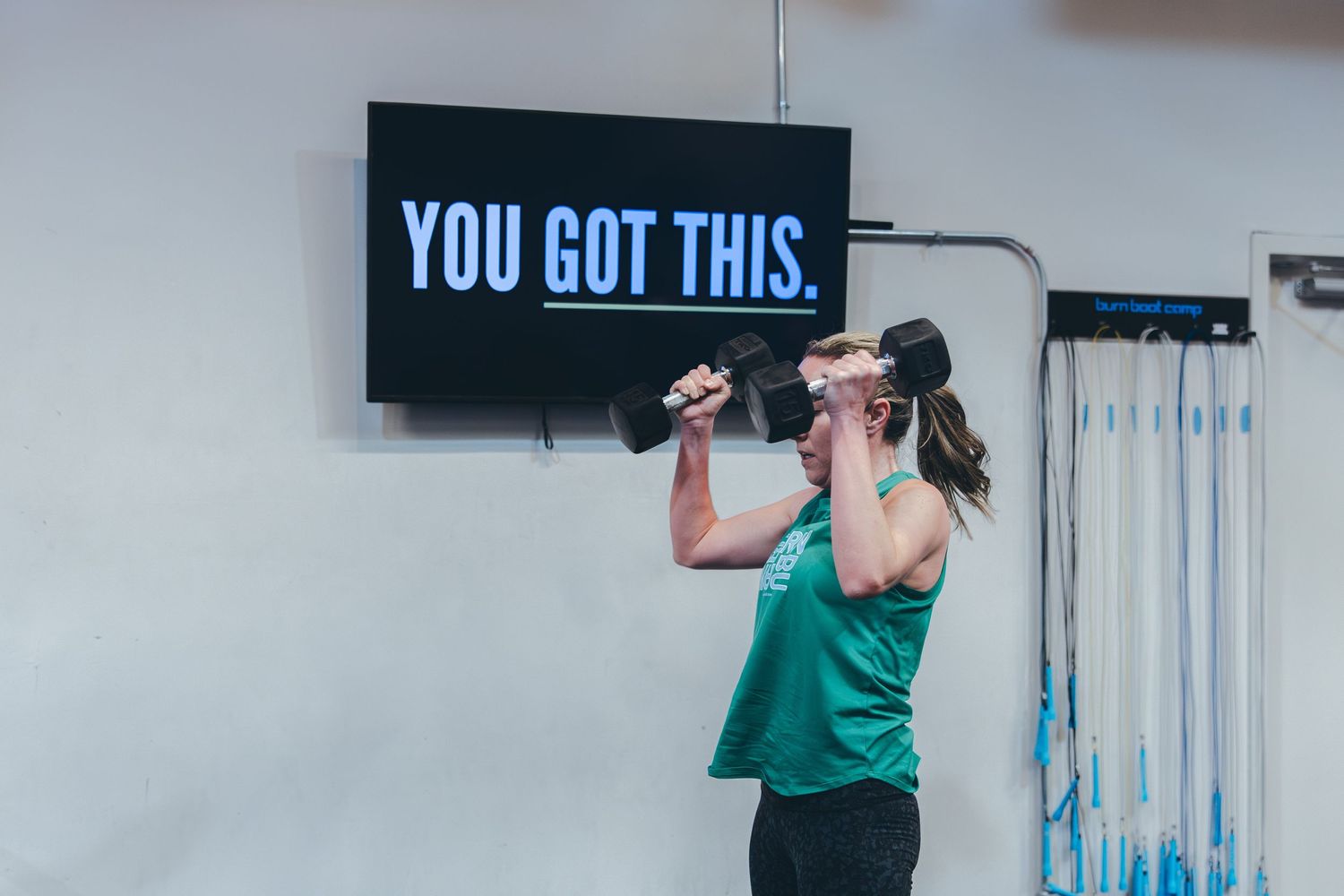 A motivational sign reading 'YOU GOT THIS' illuminates the wall of a modern fitness facility.