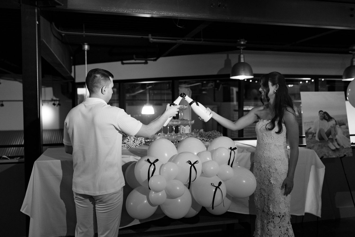 Black and white photograph showing a couple dancing at a wedding reception with balloons decorating the ceiling.
