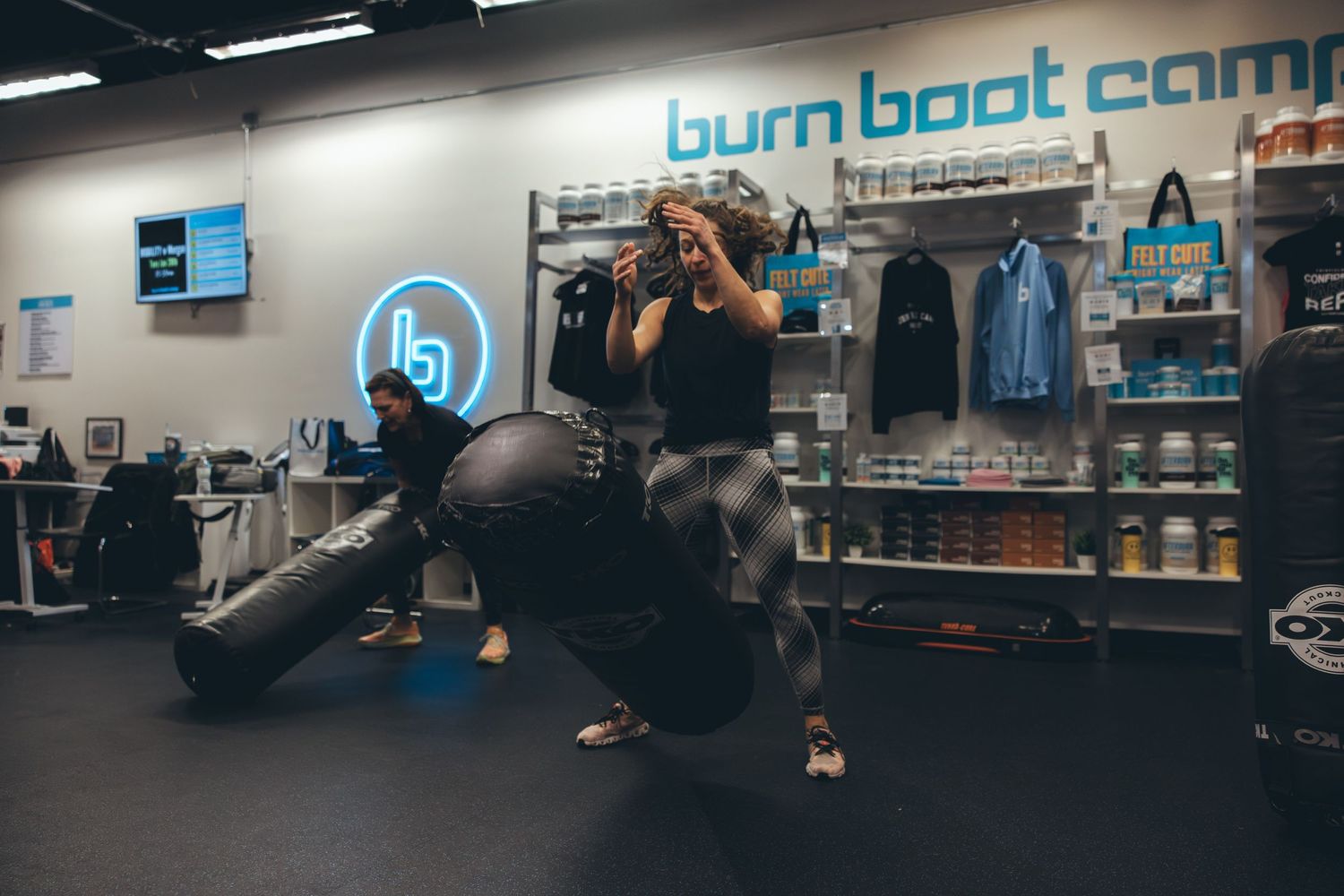 Workout session in progress at Burn Boot Camp with exercise equipment and retail display.