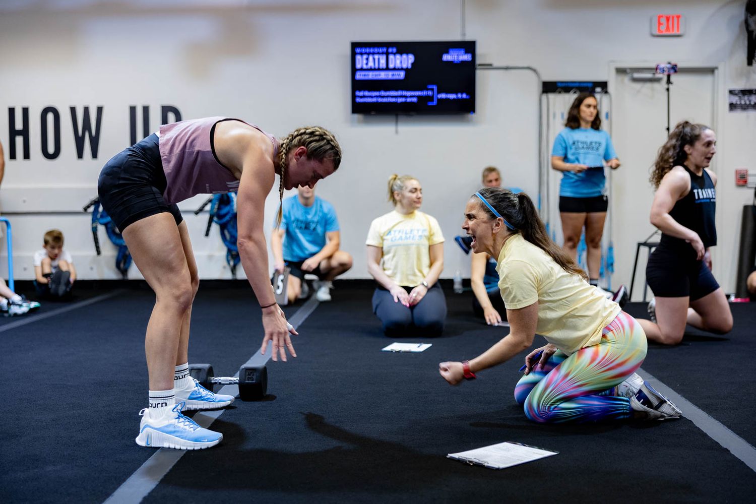Athletes practice strength and conditioning exercises in a modern gym with a digital display.
