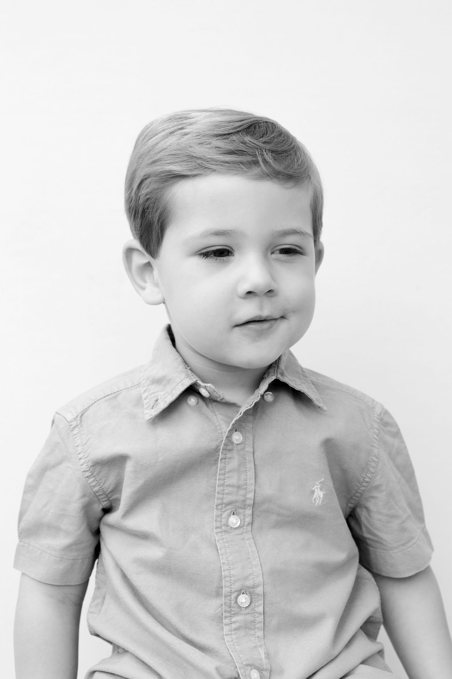 A series of black and white portraits showing a young child in a collared shirt making playful expressions.