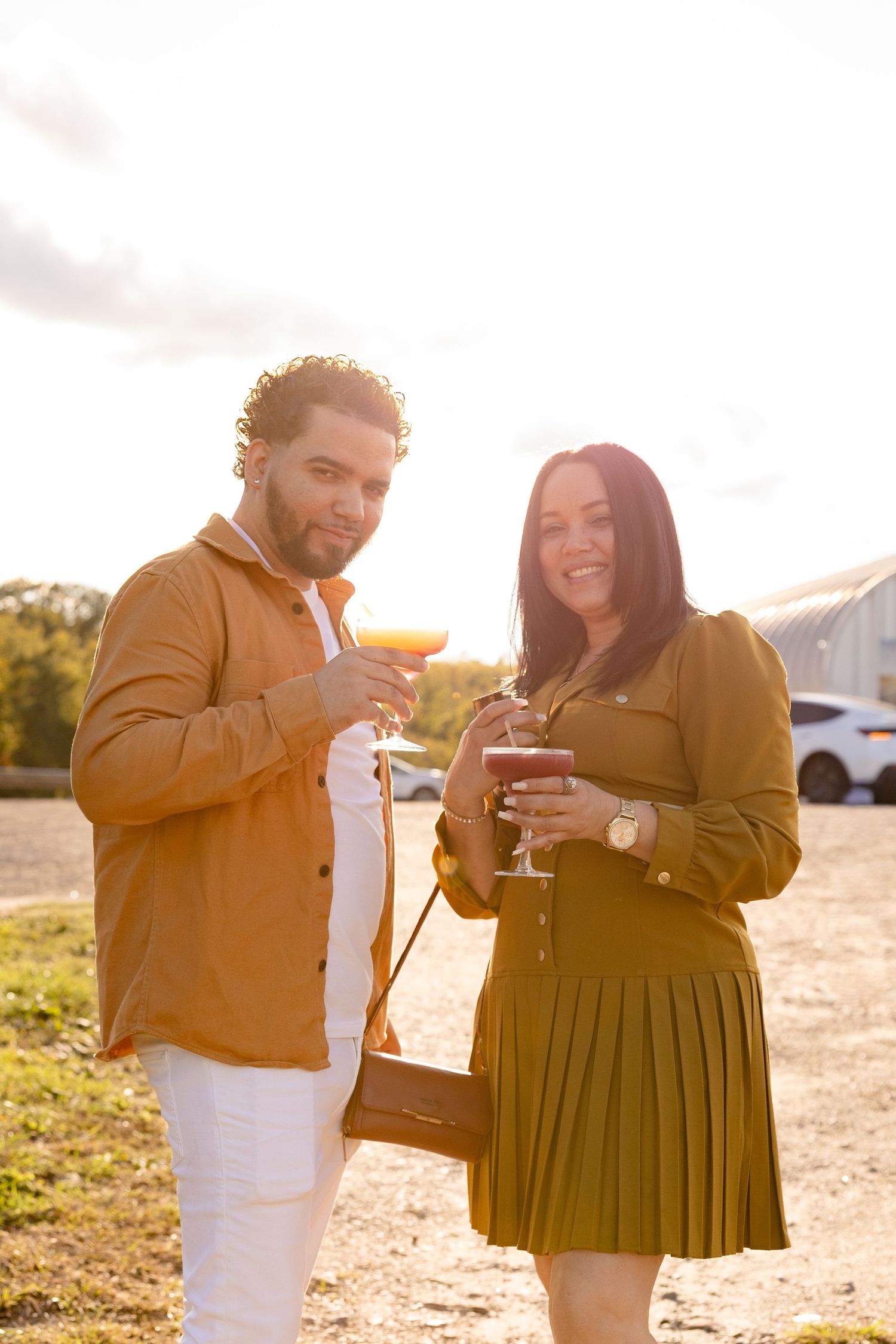 A couple laughs together during a sunset photoshoot, wearing mustard yellow and white outfits.