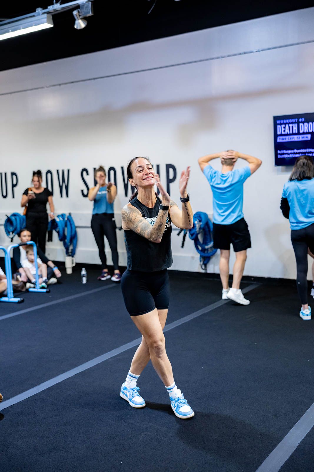 Athletes performing squat exercises during an intense group workout session in a fitness studio.