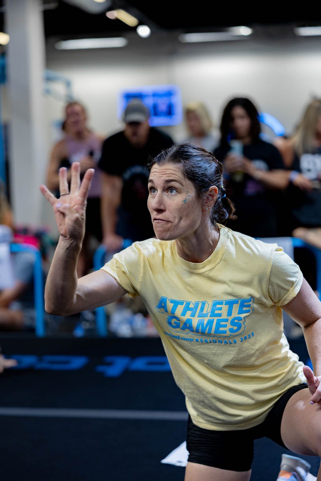 Athlete in yellow 'Athlete Games' t-shirt demonstrates proper form during competition training.