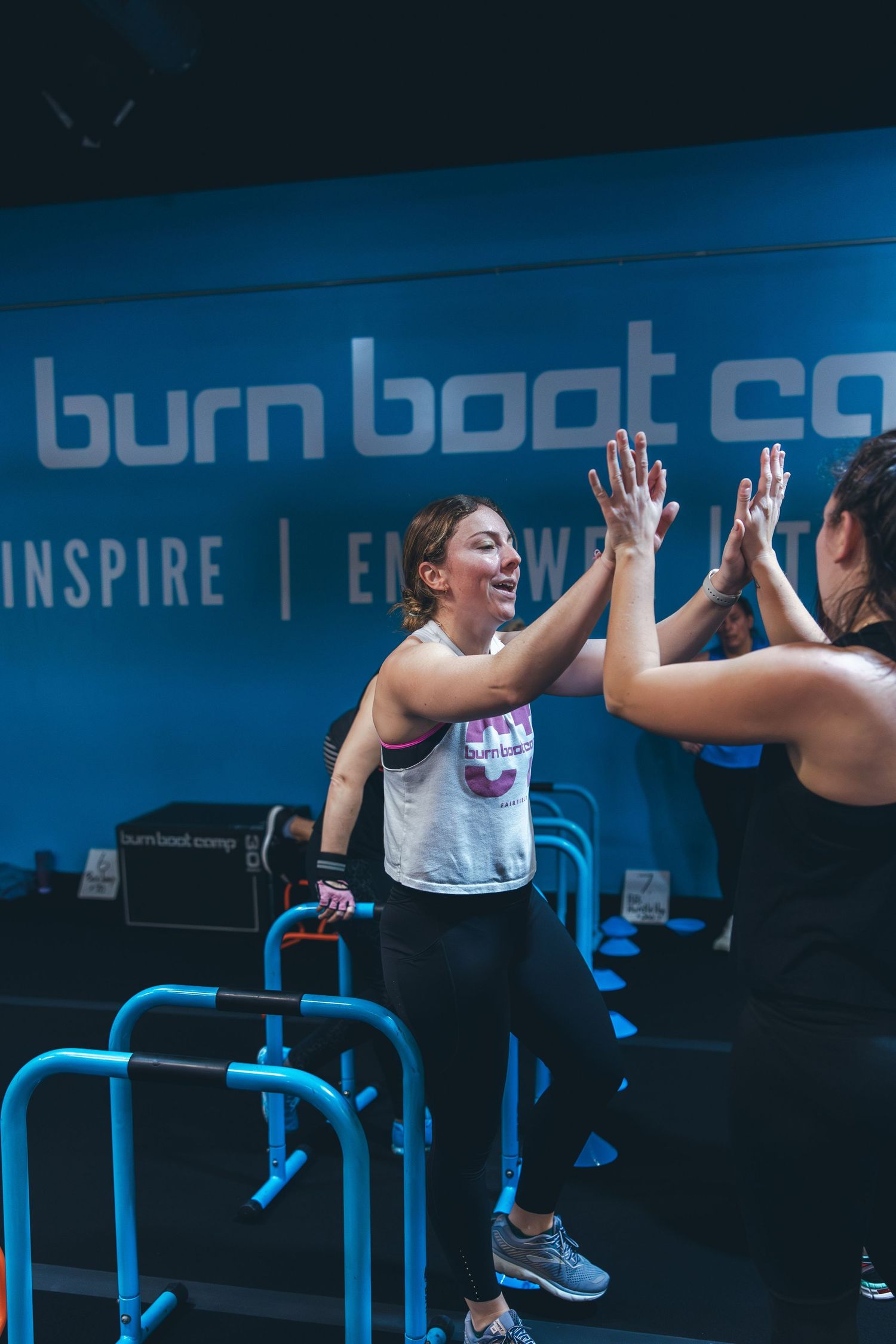 Two participants high-five during energetic workout session at burn boot camp.