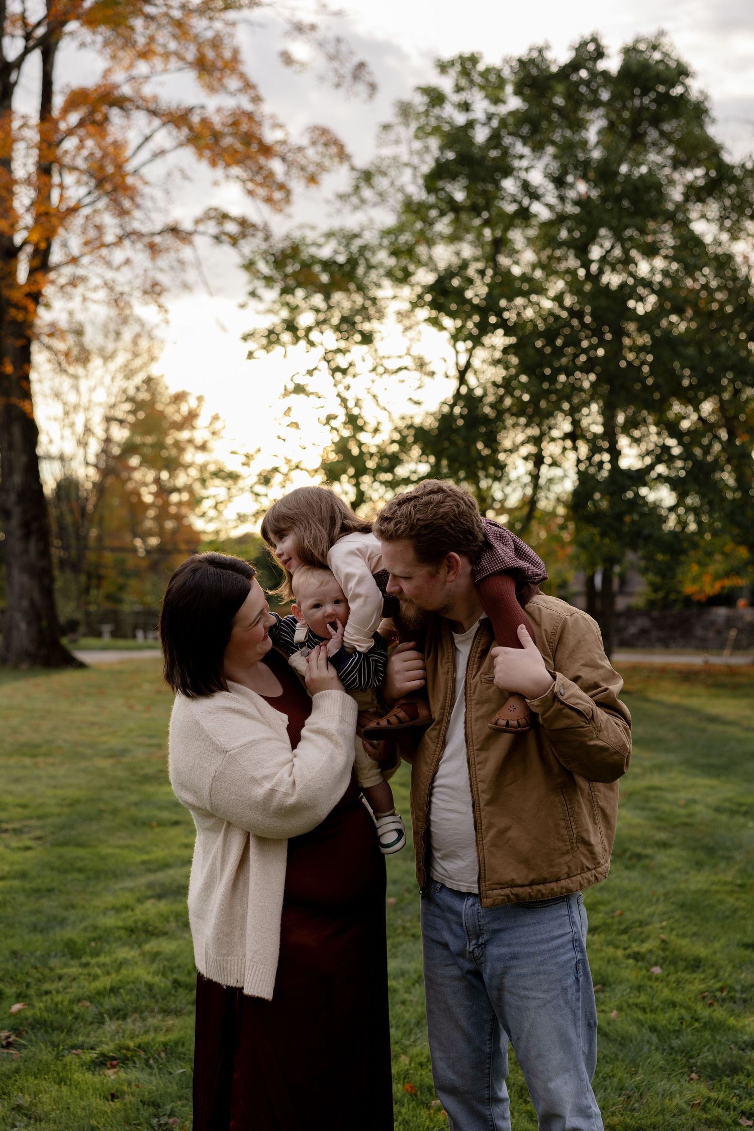 A group of people share joyful laughter together in a sunlit autumn field during golden hour.