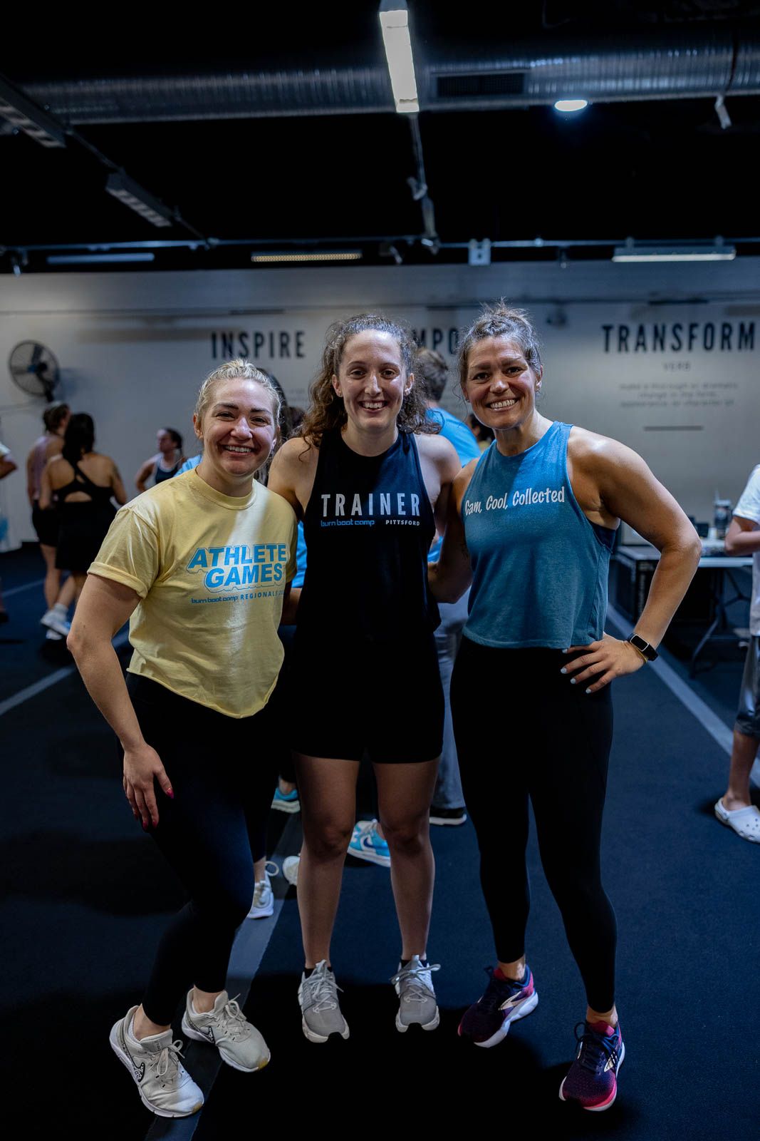 Gym members posing together during a fitness class in a modern training facility with blue flooring.