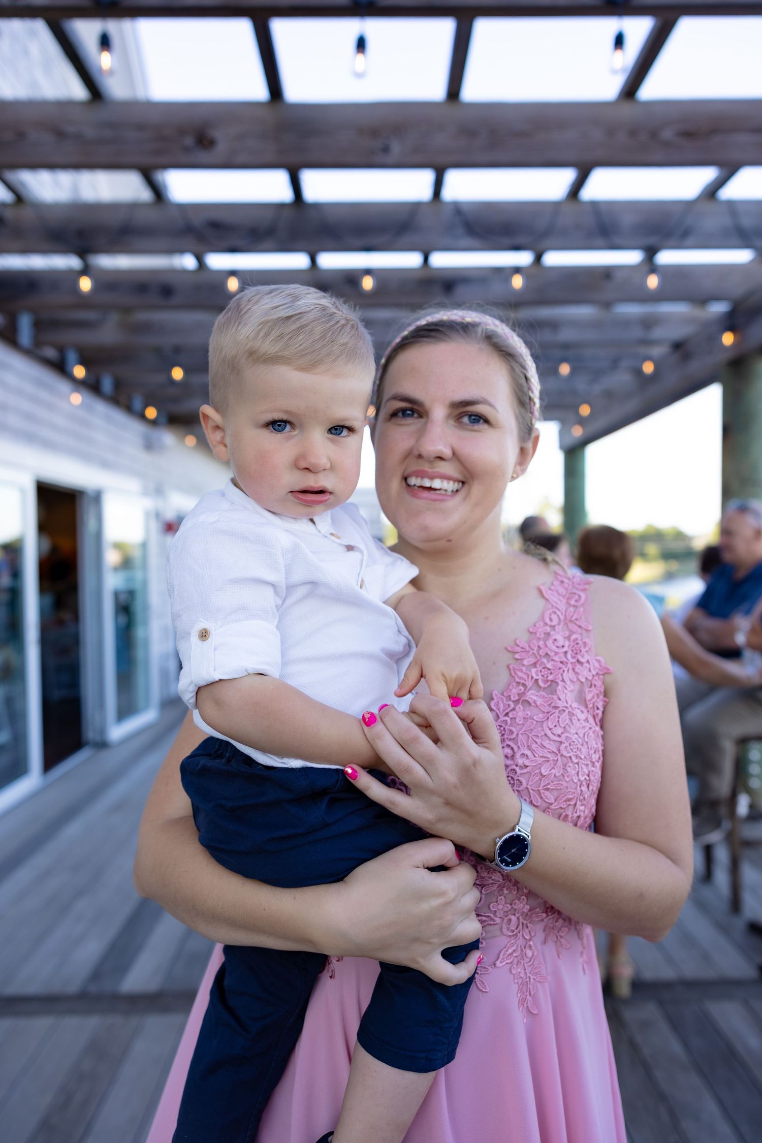 A series of tender moments captured on a covered outdoor deck with string lights overhead.