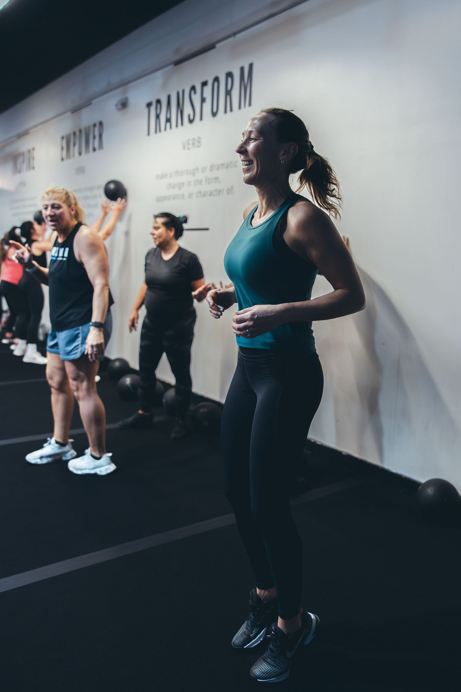 Participants engaged in medicine ball exercises during fitness class at transformer gym.