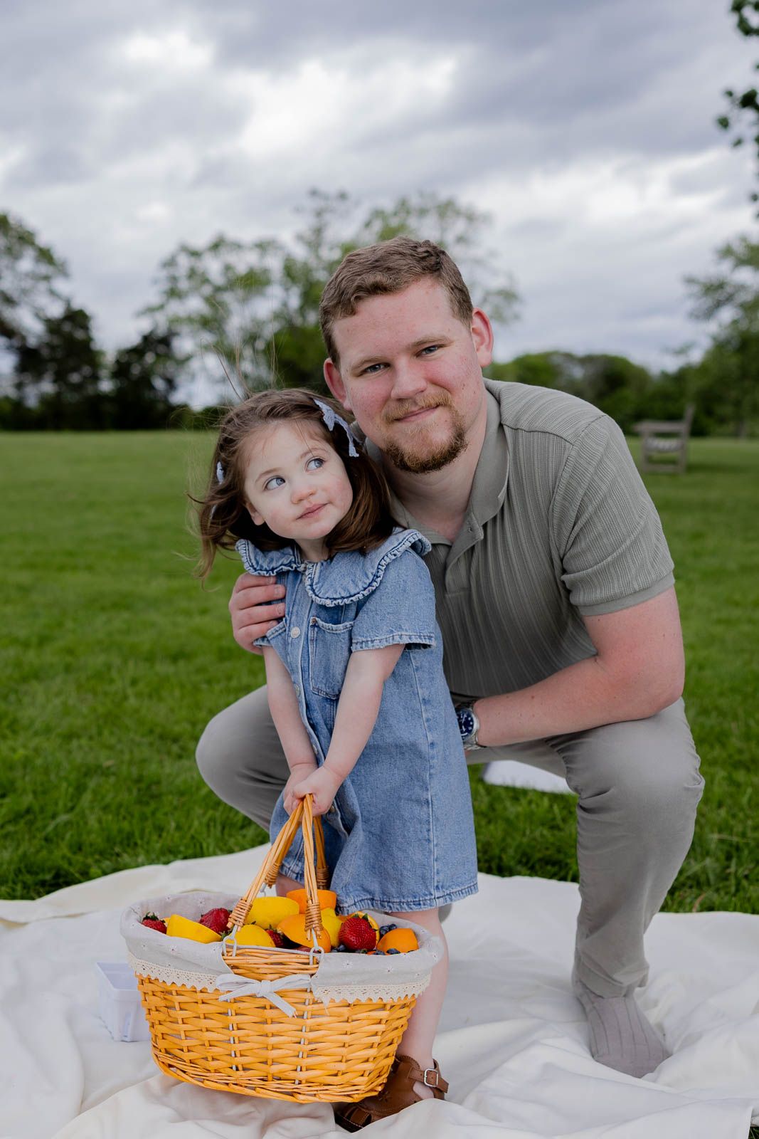 A heartwarming picnic scene with a wicker basket full of fruit on a blanket in a grassy park.