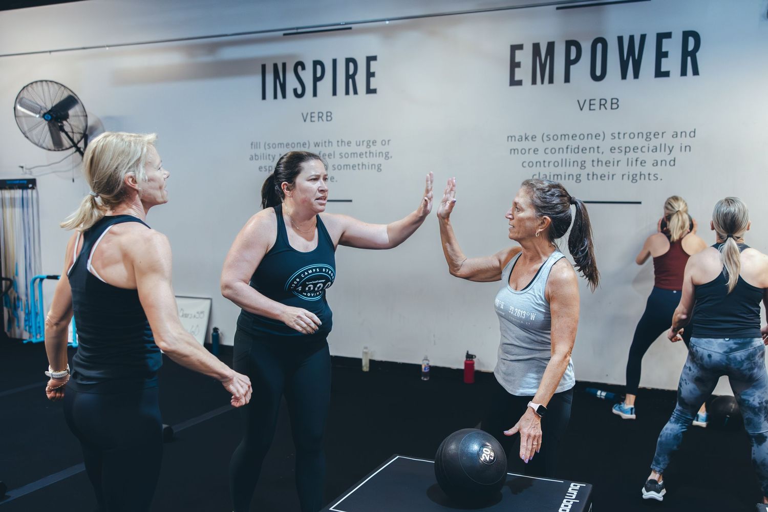 Participants celebrating and high-fiving during an indoor fitness class.