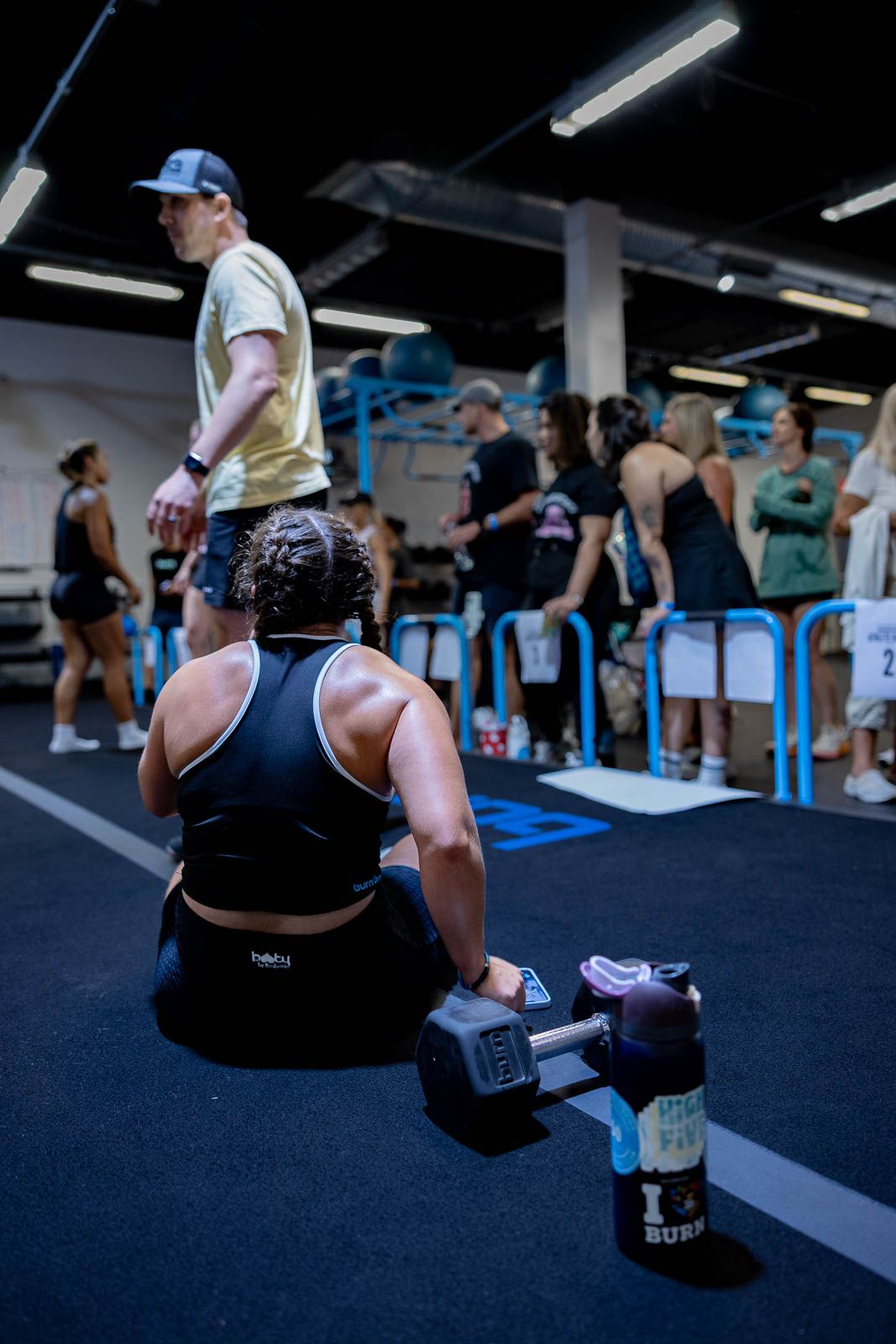 People working out in a dark gym with fluorescent lighting and blue accents on the equipment.