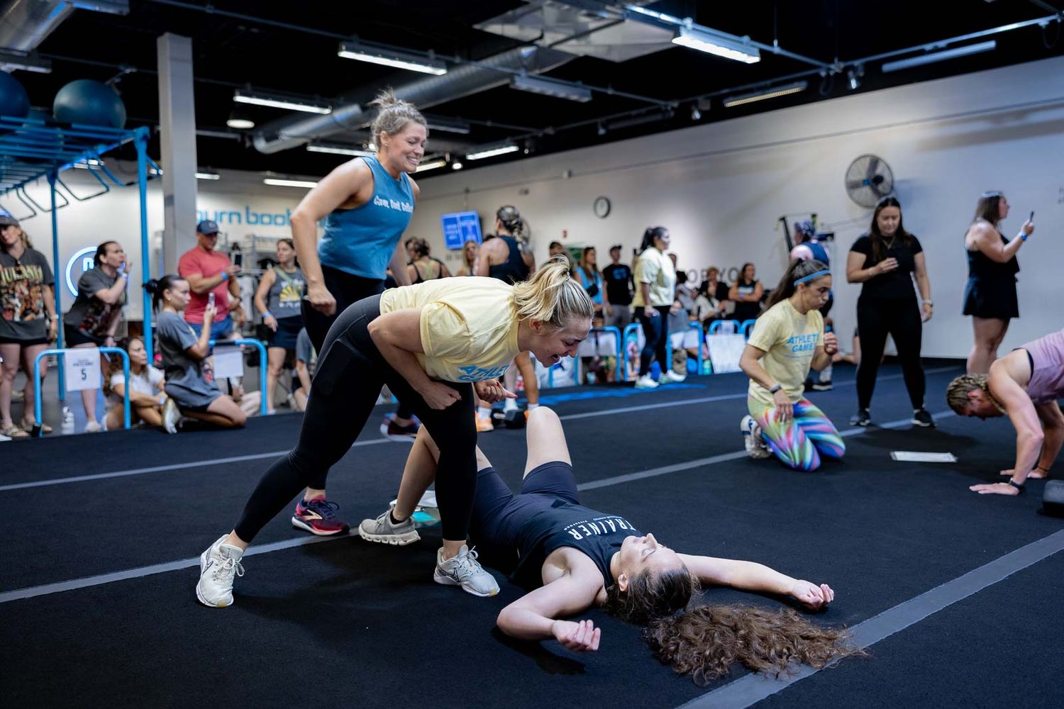 Participants perform exercises with partners during an intense workout session at a CrossFit-style fitness class.
