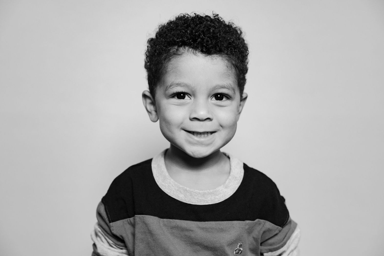 Black and white headshot portrait of a young child smiling at the camera.