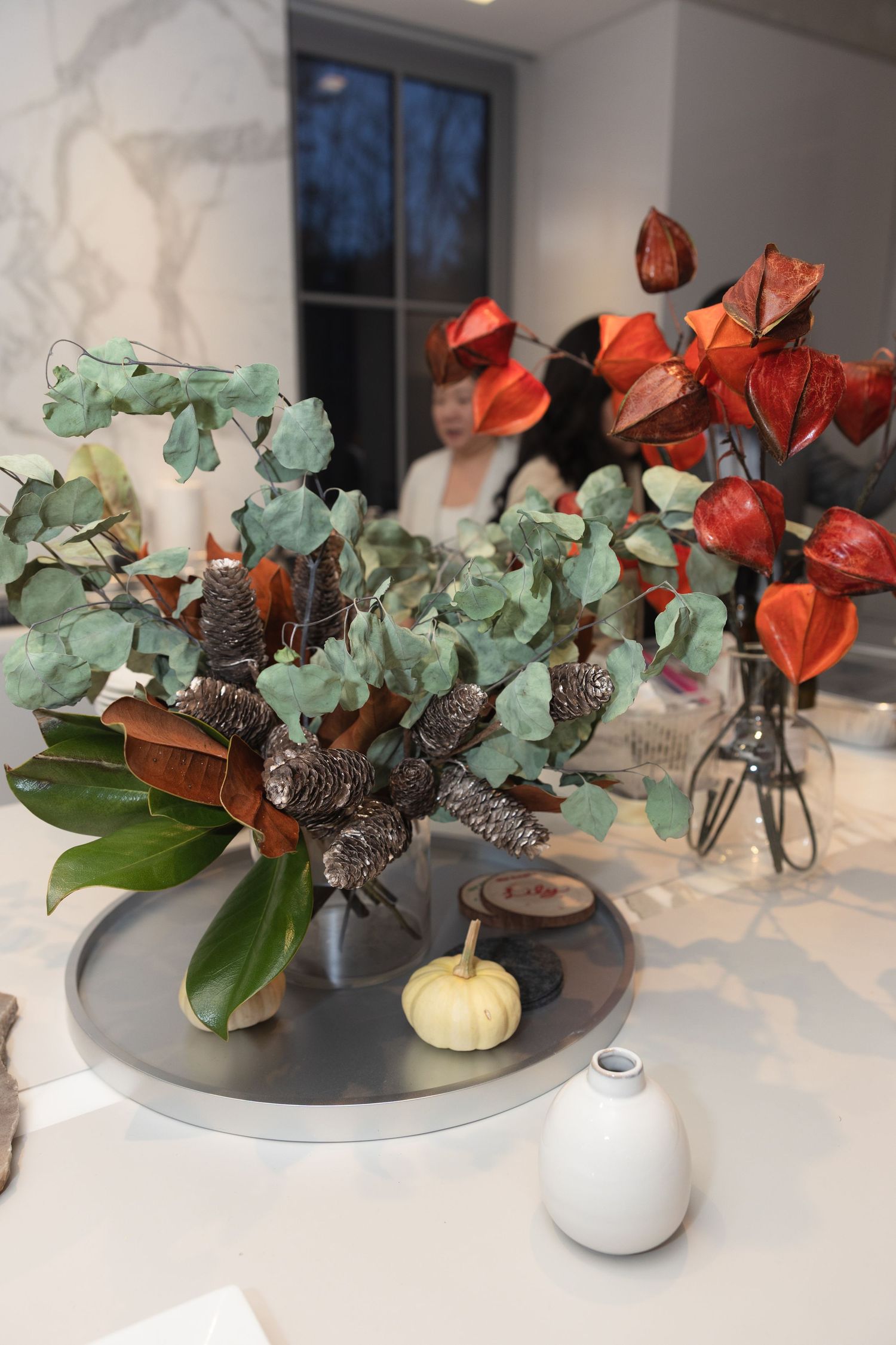 A series of modern floral arrangements with red and mint green flowers in white and gray vases on a white surface.