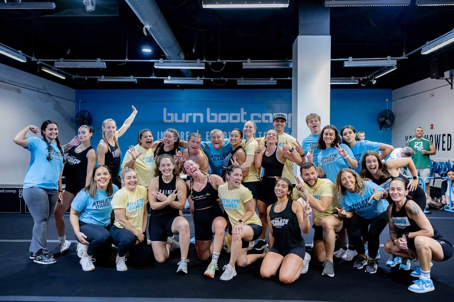 Large group of enthusiastic fitness participants celebrating together at a Burn Boot Camp gym facility.