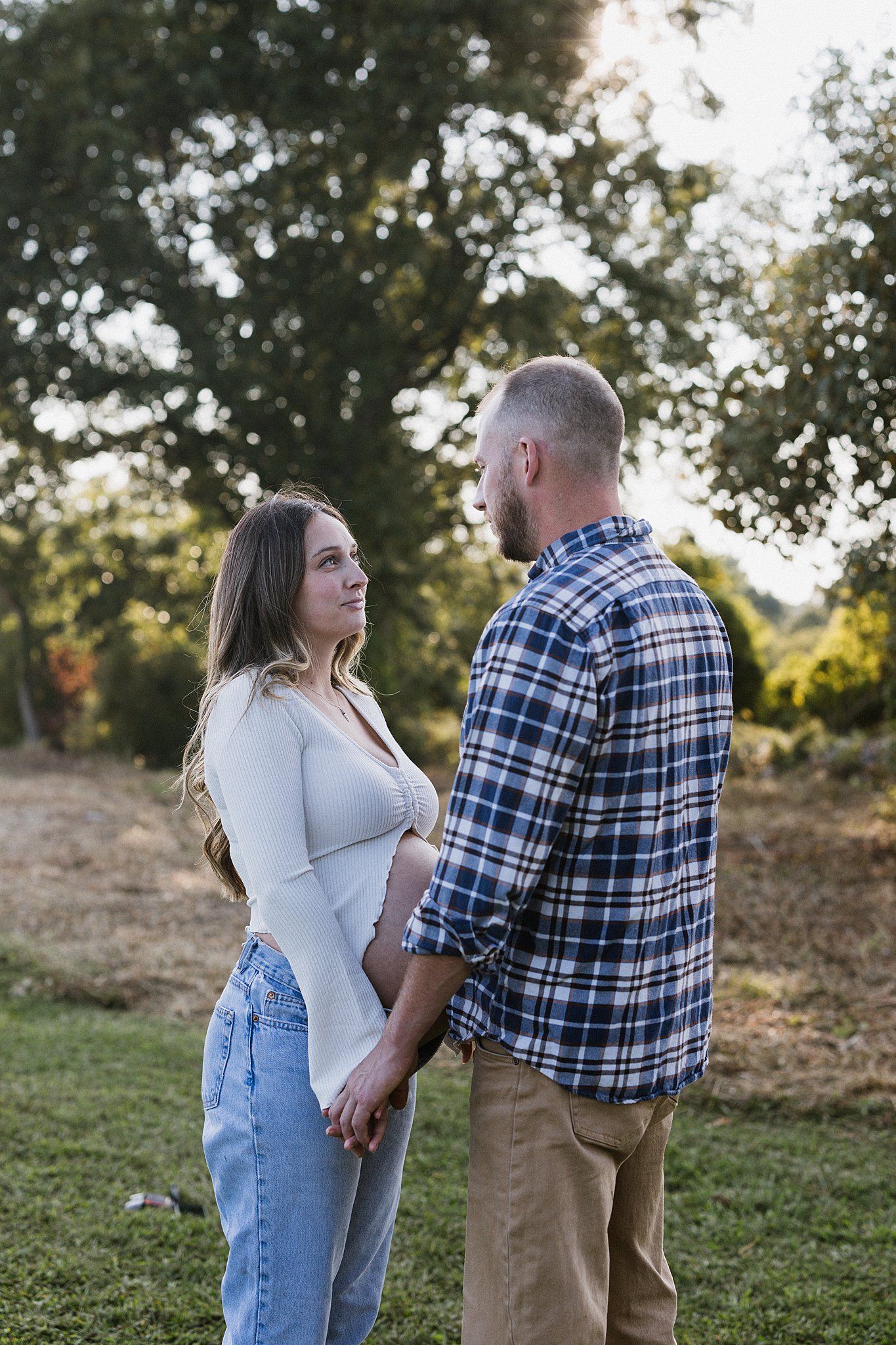 Couple in casual attire sharing an intimate moment outdoors during a sunset photoshoot.