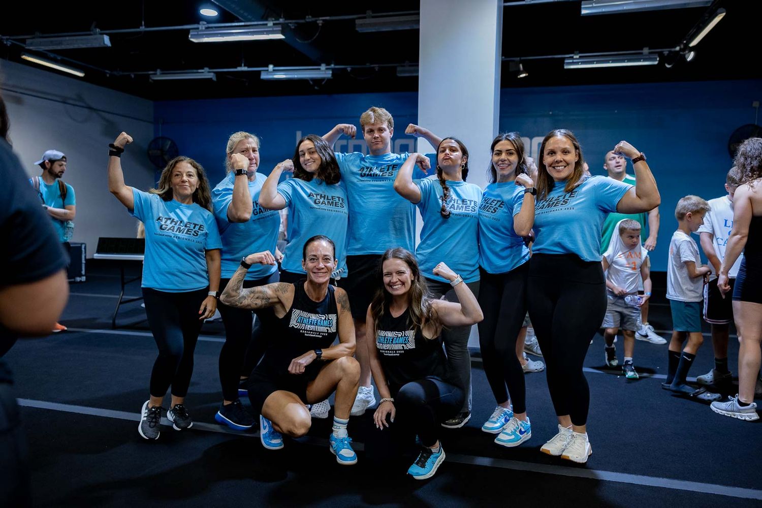 Group fitness class participants perform exercises on blue floor mats in a modern gym setting.