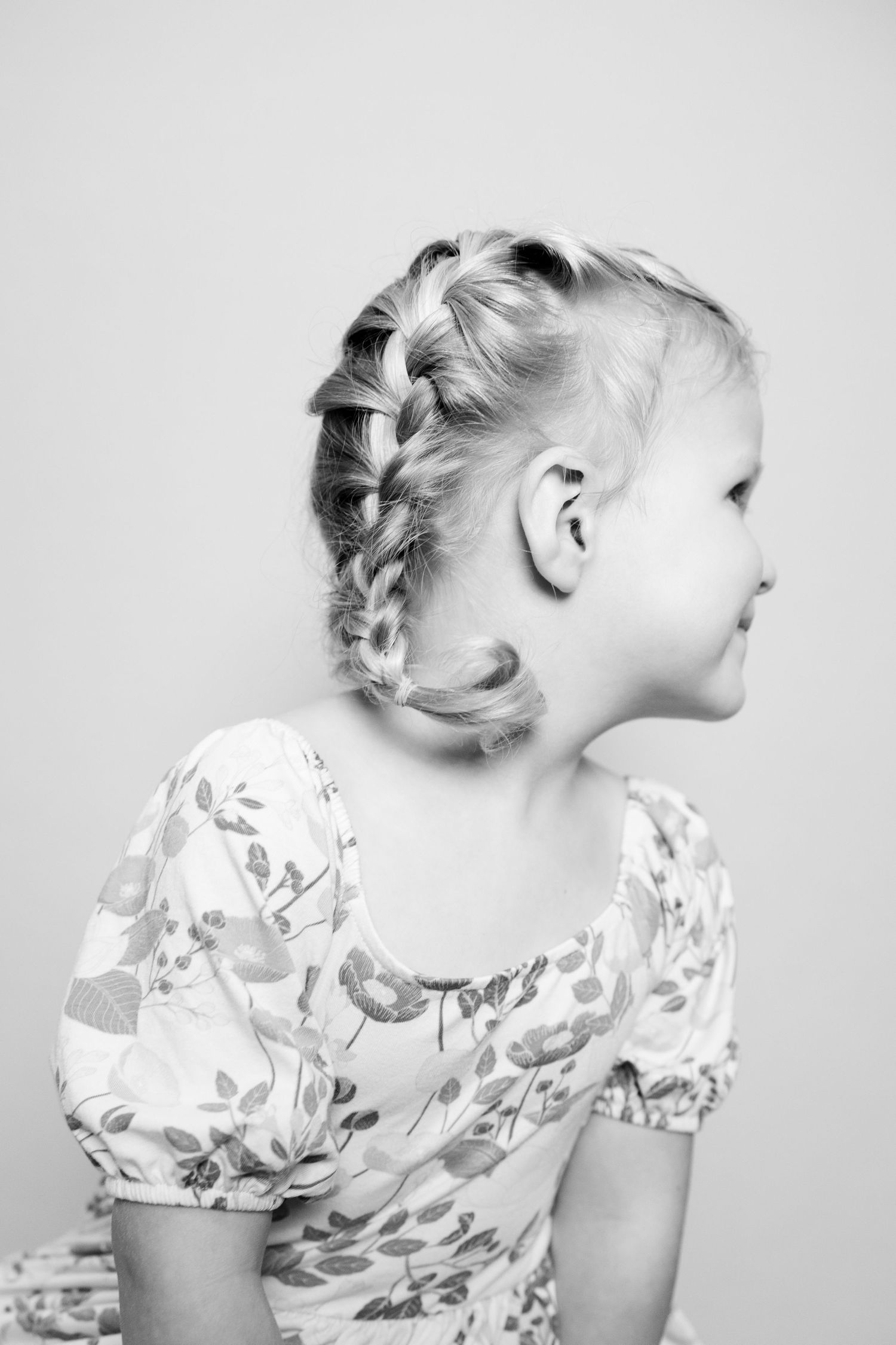 A series of black and white profile portraits showing braided hairstyles and floral print clothing.
