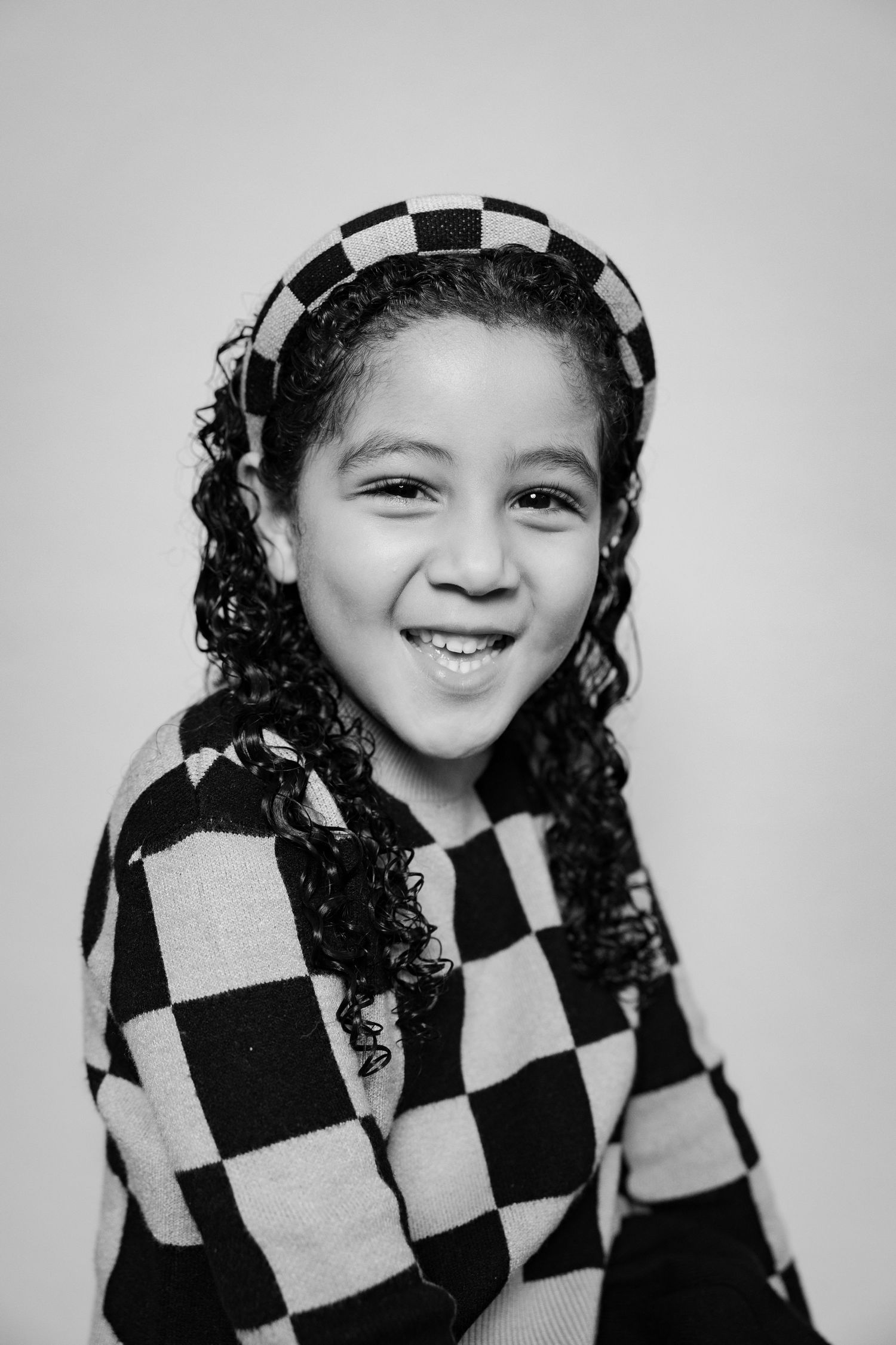 A black and white photo series shows someone wearing a checkered outfit while making playful expressions.