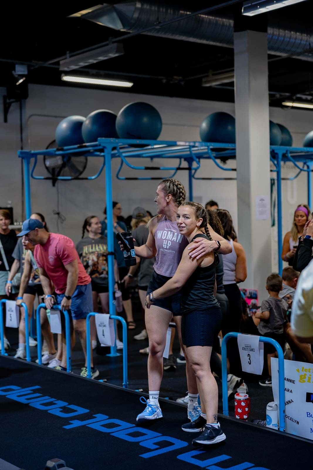 Athletes celebrating and embracing after a workout in a gym with blue exercise equipment.