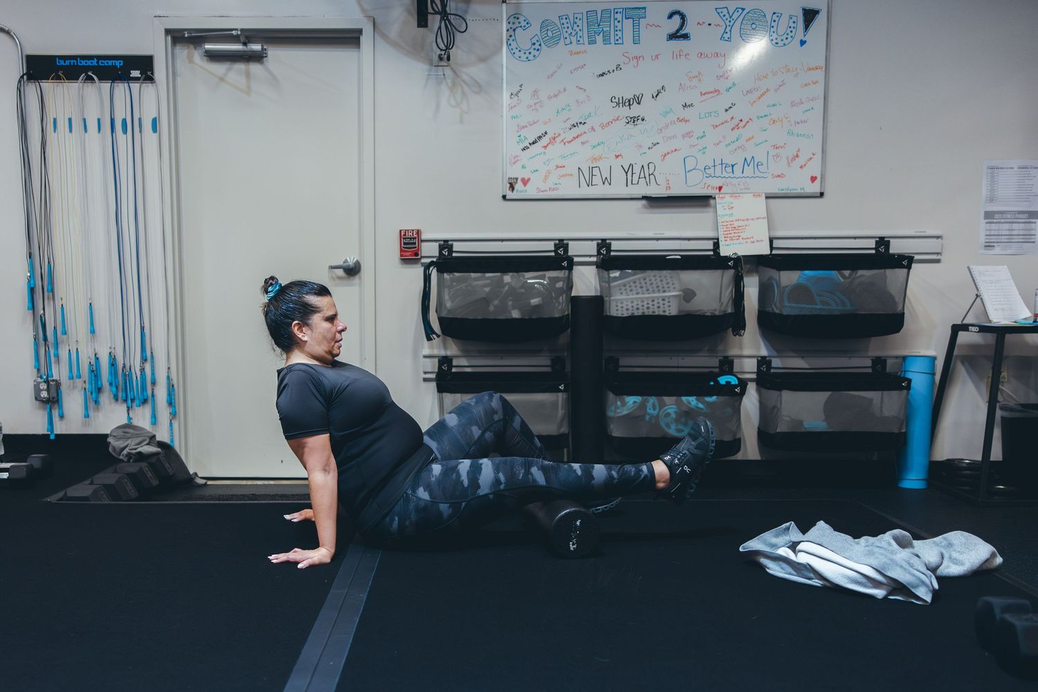 Person performing a plank exercise on a dark gym floor with equipment in the background.