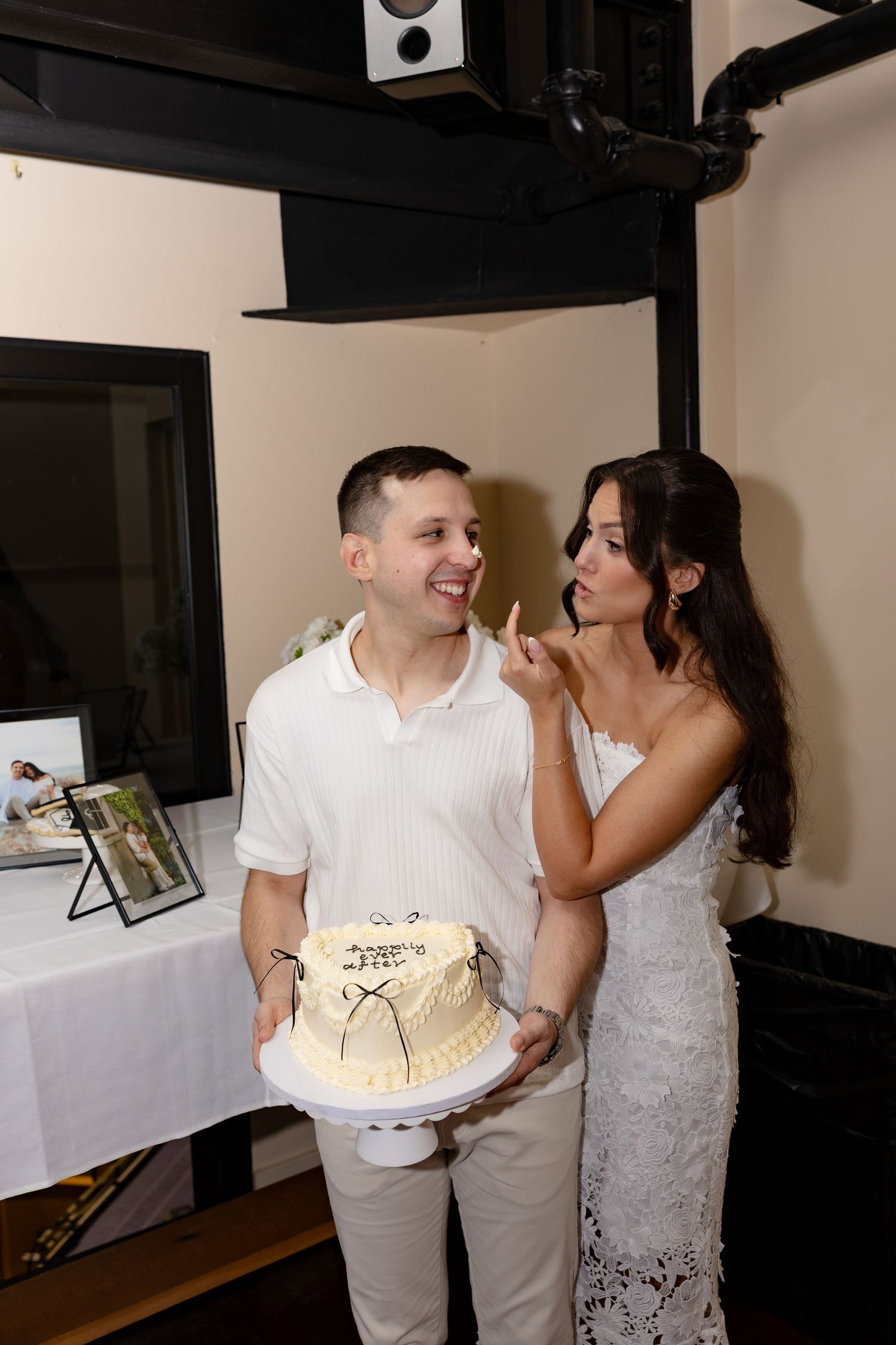 Couple sharing a sweet moment with wedding cake at indoor celebration venue.