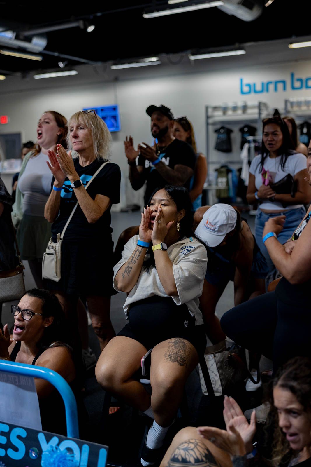 Enthusiastic crowd cheering and showing emotions at a sports or entertainment event at a venue with blue lighting and signage.