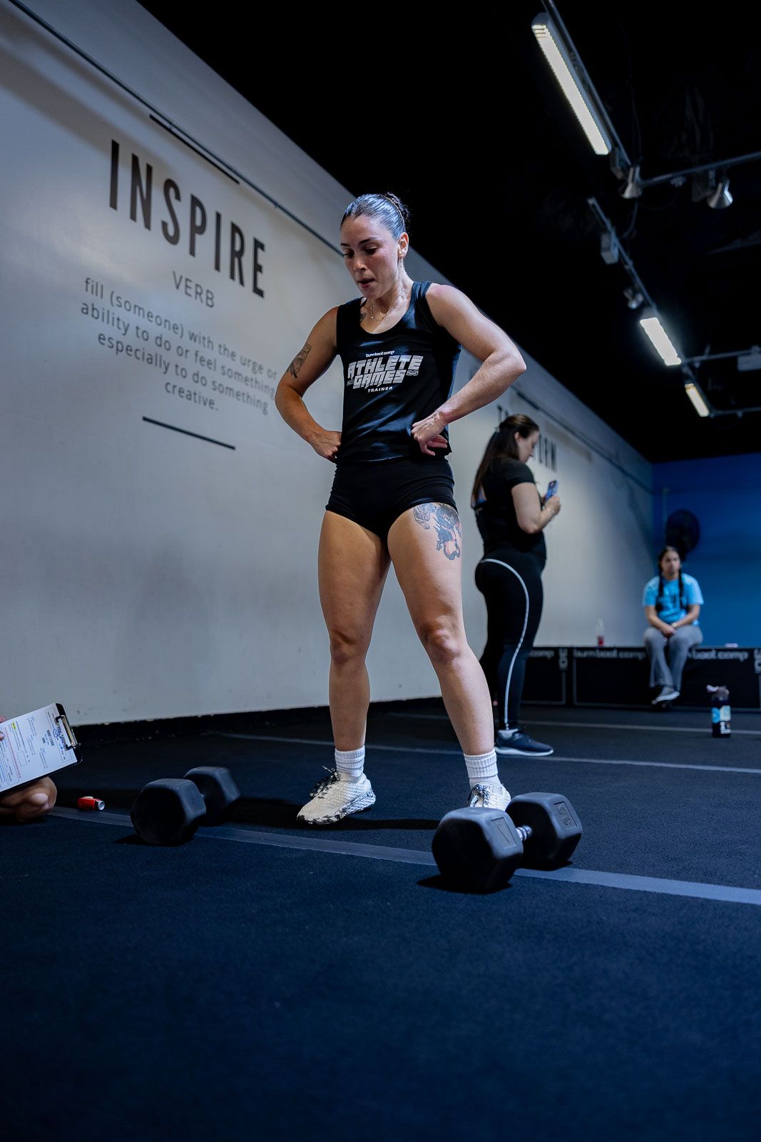 Athlete taking break between sets near dumbbells in gym with 