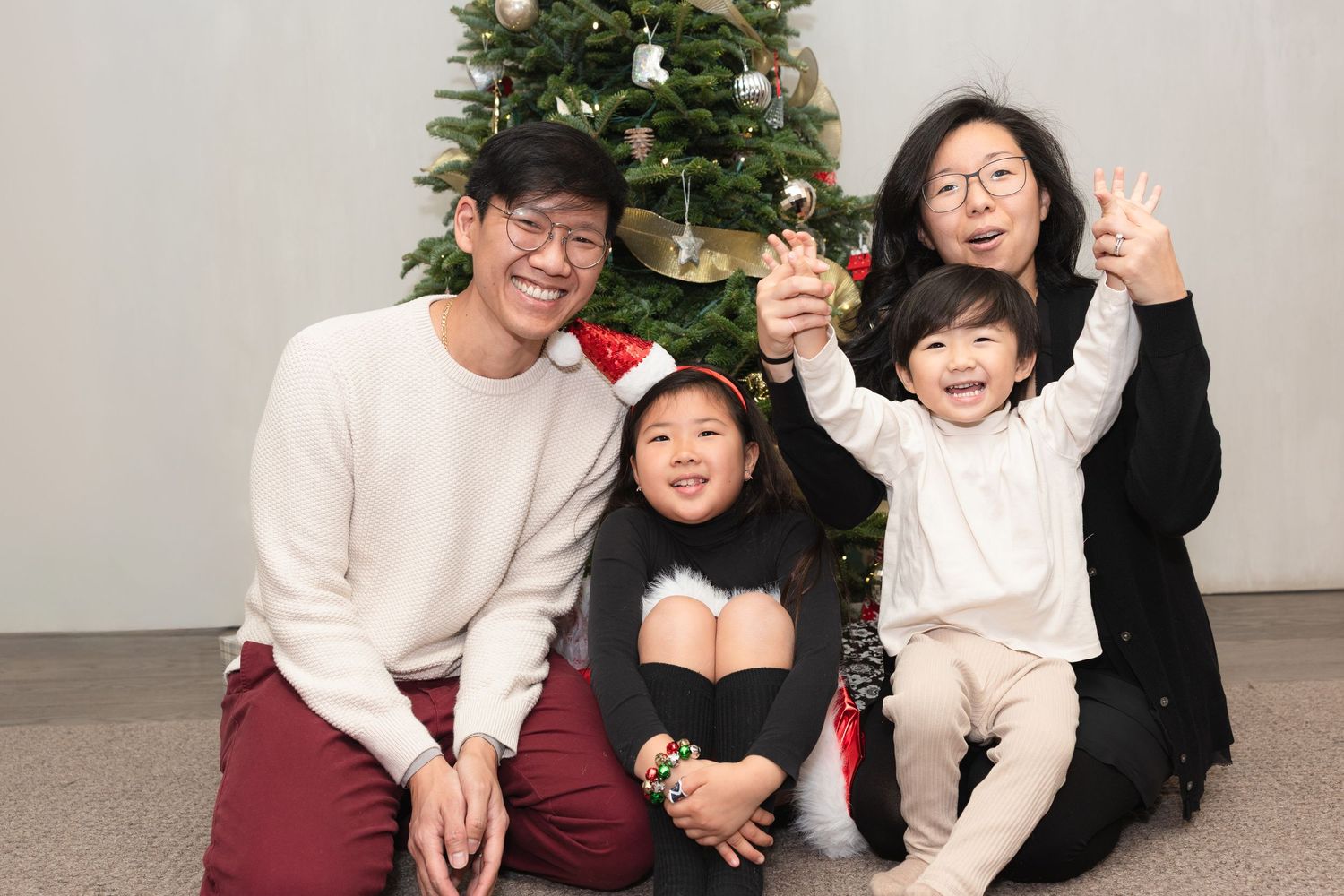 A group of friends pose together for holiday photos in front of a decorated Christmas tree.