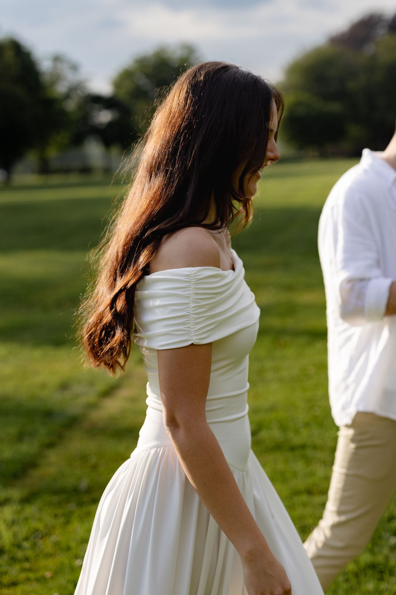 A person in a white dress stands in a grassy field on a sunny day with blurred motion captured in sequence.