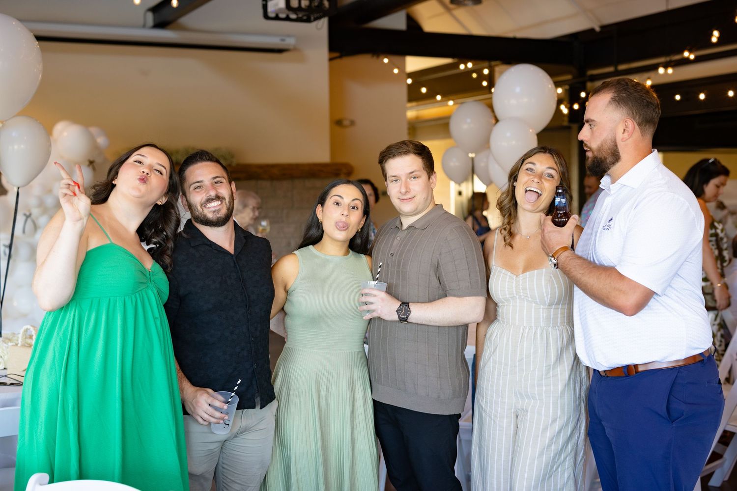 Wedding reception guests dancing and socializing in a venue decorated with string lights.